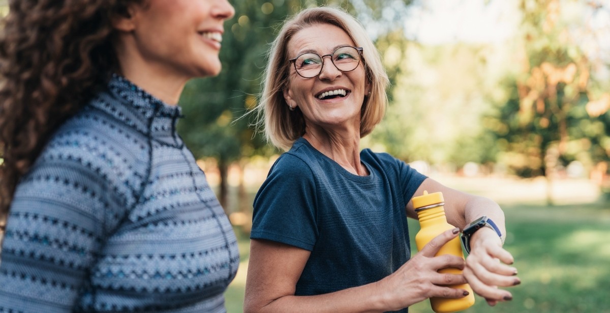 Healthy habits: two people outdoors in a park, one checking a smartwatch.