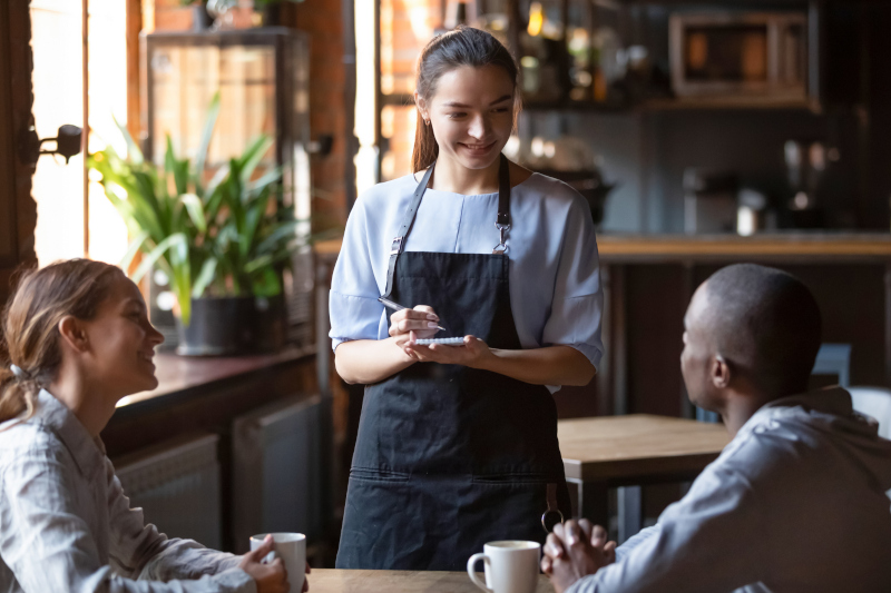 Waitress taking an order in a restaurant from two people.